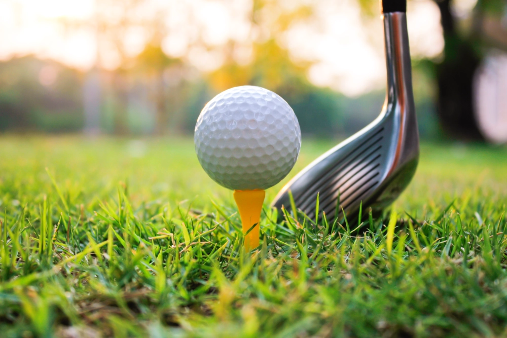 Golf ball on tee with club nearby.